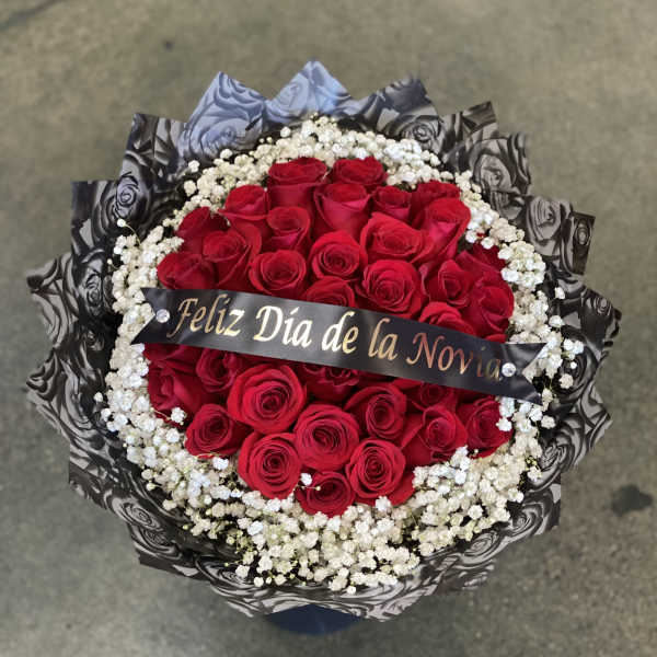 Round bouquet of red roses with white baby's breath and a ribbon