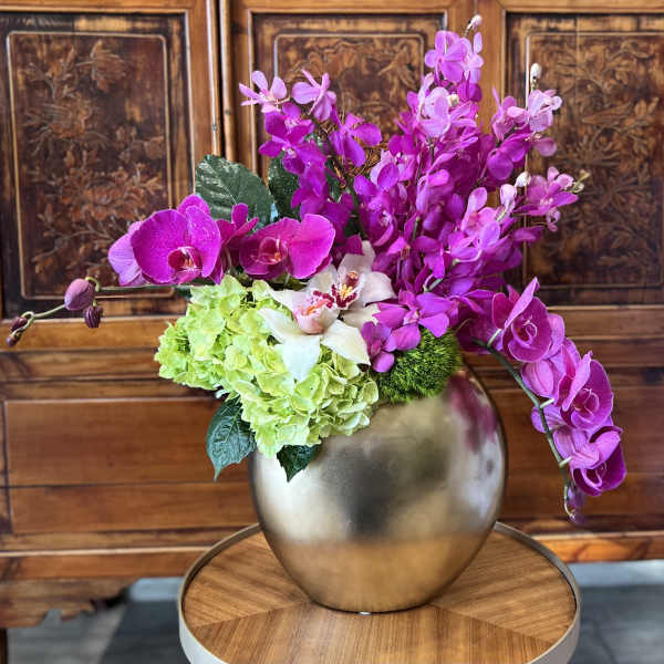 Pink orchids and green hydrangeas in a gold vase