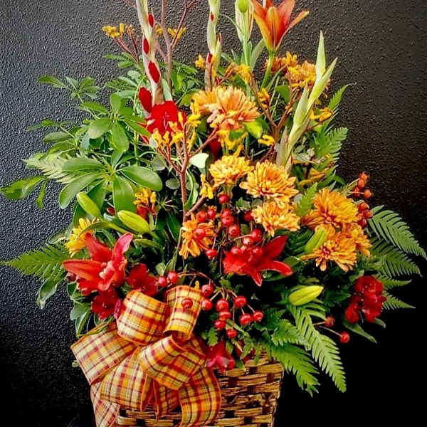Autumn flower basket with orange lilies, yellow mums, and a plaid bow