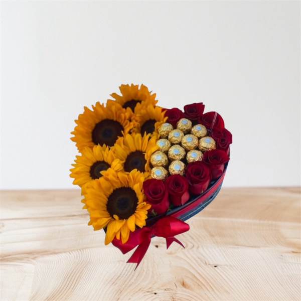 Heart-shaped bouquet of sunflowers, red roses, and chocolates with a red ribbon