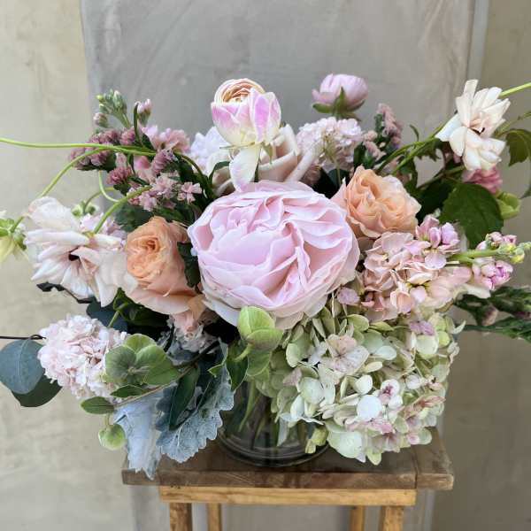 Pink and peach roses arranged with hydrangeas in a glass vase