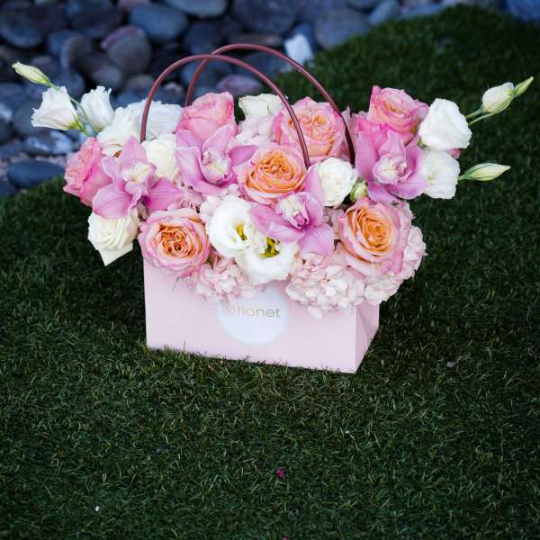 Pink and white floral arrangement in a pink gift box with handles