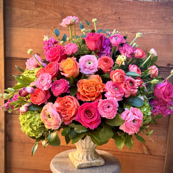Mixed pink and orange flower arrangement in a stone vase