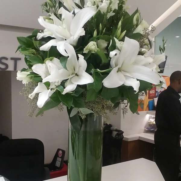 Tall white lily arrangement in a clear glass vase