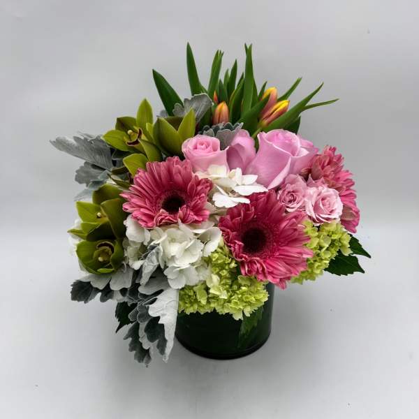 Pink roses and gerbera daisies arranged in a dark vase