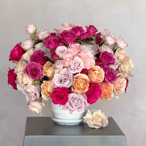 Bouquet of pink, peach, and cream roses in a white vase