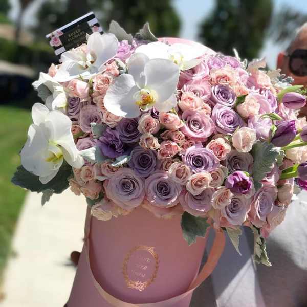 Pink and lavender rose bouquet in a pink hatbox with white orchids