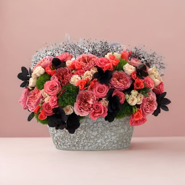 Pink and coral rose arrangement in a textured silver container