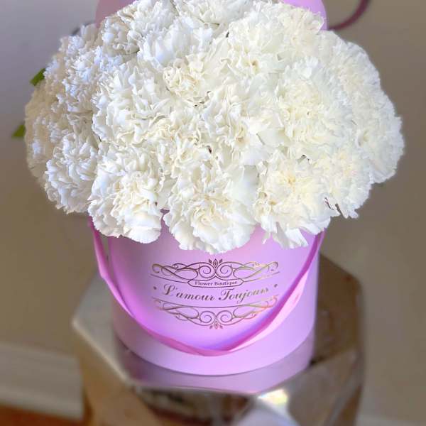 White carnation bouquet in a pink hatbox with ribbon handle