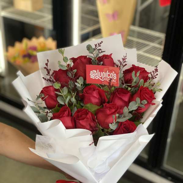 Bouquet of red roses wrapped in white paper with a red ribbon