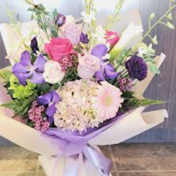 Bouquet of pink, purple, and white flowers wrapped in lavender paper