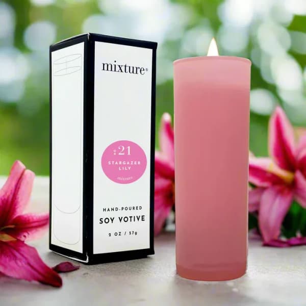 Pink soy votive candle beside its box with stargazer lilies in the background