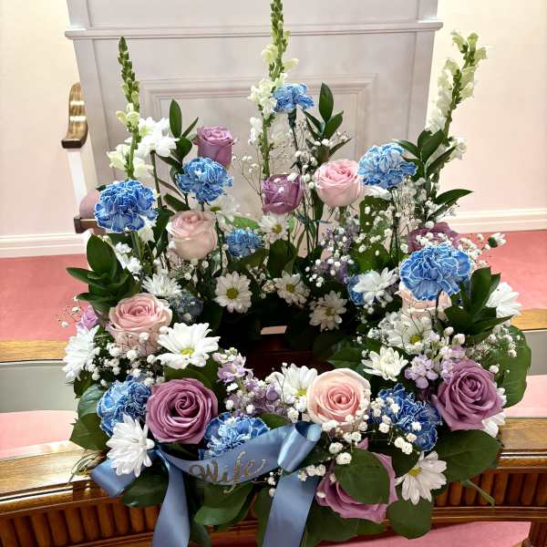 Floral wreath with pink and purple roses, blue carnations, and white daisies