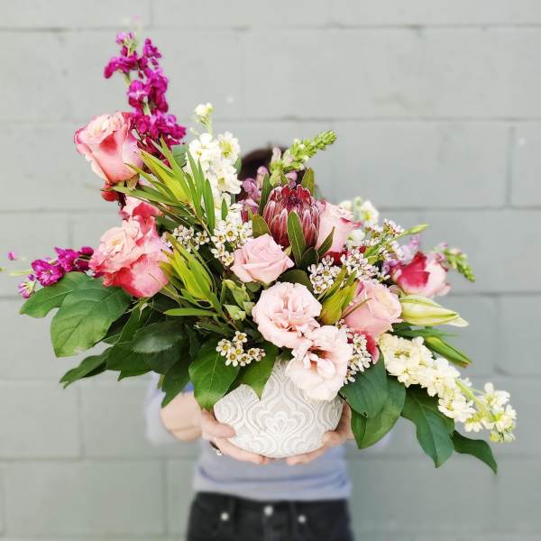 Pink and white mixed flower arrangement in a white ceramic vase