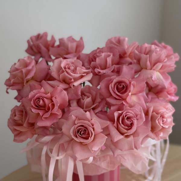 Pink rose bouquet in a striped round box with ribbon tails