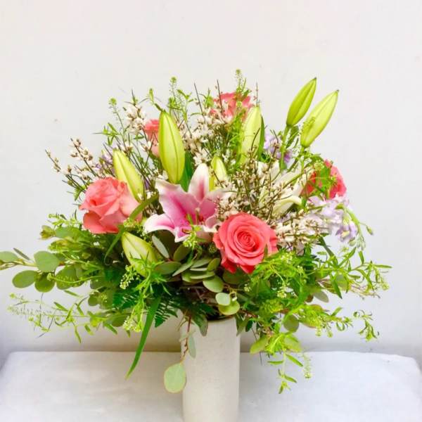 Pink roses and lilies arranged in a white vase