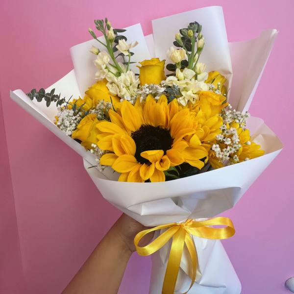 Yellow sunflower bouquet wrapped in white paper with a yellow ribbon