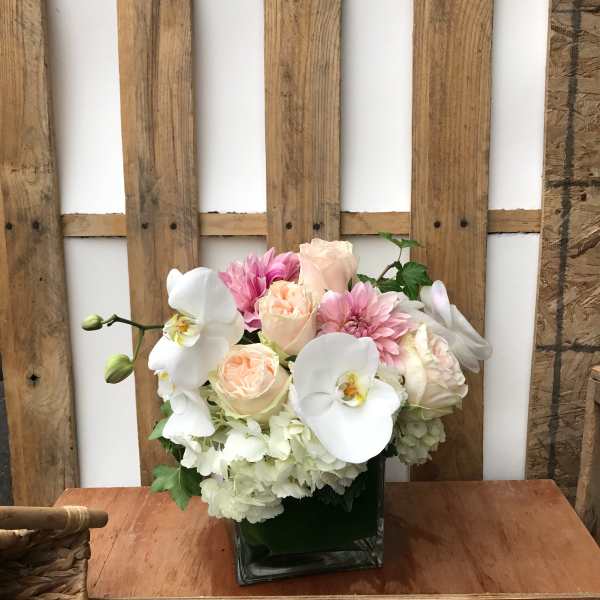 Pink and white floral arrangement in a square glass vase