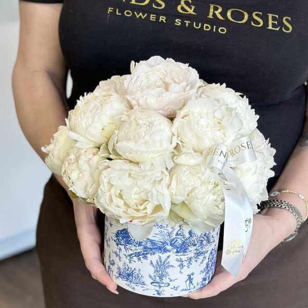 White peonies arranged in a blue-and-white round box with a ribbon