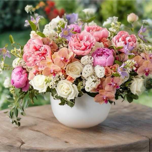 Pink and white floral arrangement in a white bowl vase