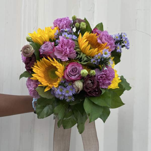 Bouquet of sunflowers, purple roses, and lavender flowers