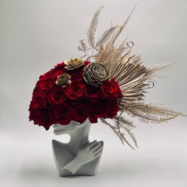 Red rose arrangement in a gray sculptural vase with gold dried accents