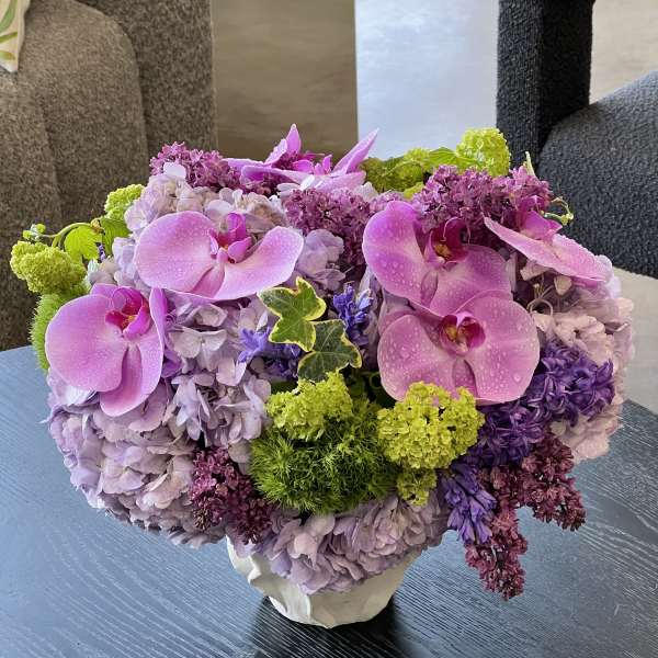 Pink orchids and lavender hydrangeas in a white vase