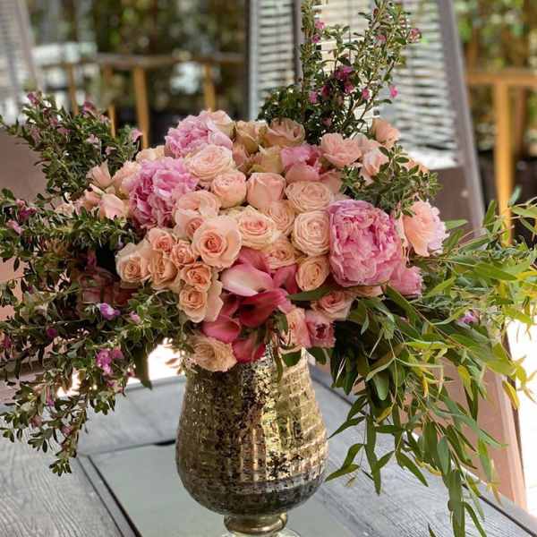 Pink and peach floral arrangement in a metallic vase