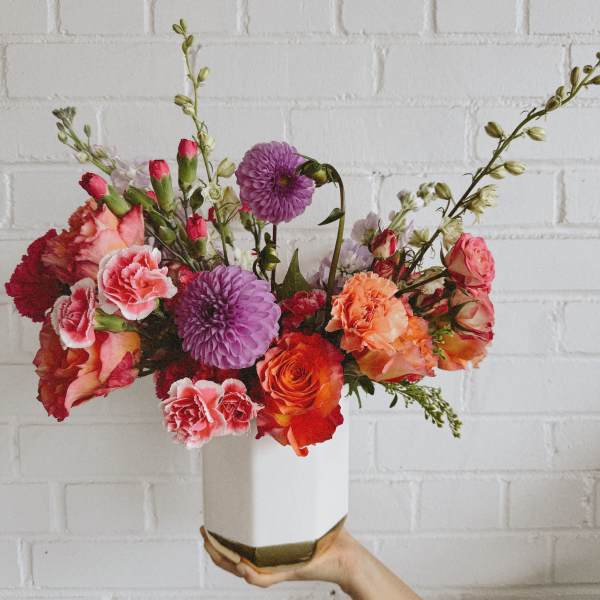 Colorful bouquet in a white vase with pink, orange, and purple blooms