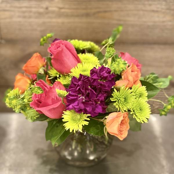 Colorful mixed bouquet in a glass vase with roses and mums