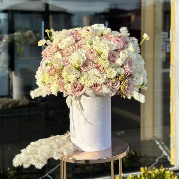 Large pastel bouquet of roses and white blooms in a white hatbox