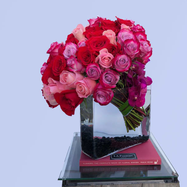 Bouquet of red, pink, and purple roses in a clear glass vase