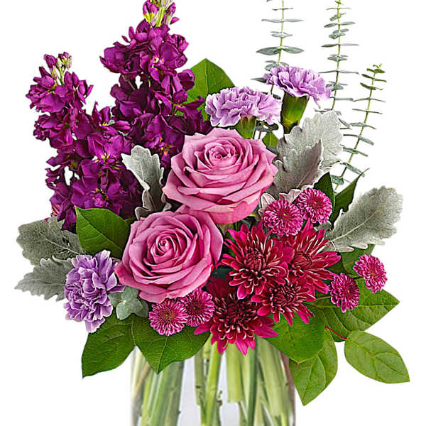 Pink roses and purple flowers in a clear glass vase