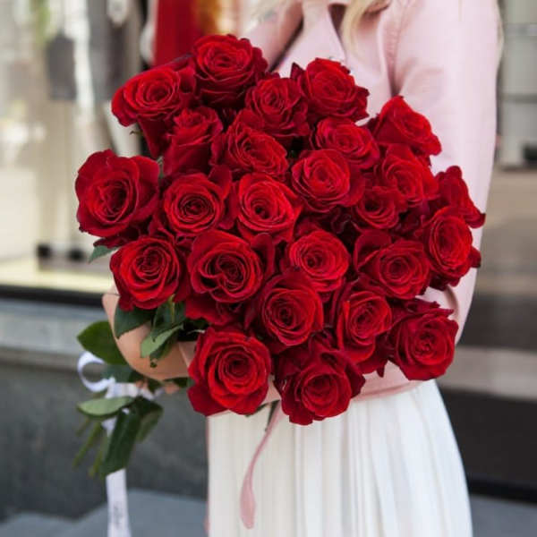 Large bouquet of red roses held by a person in a light dress