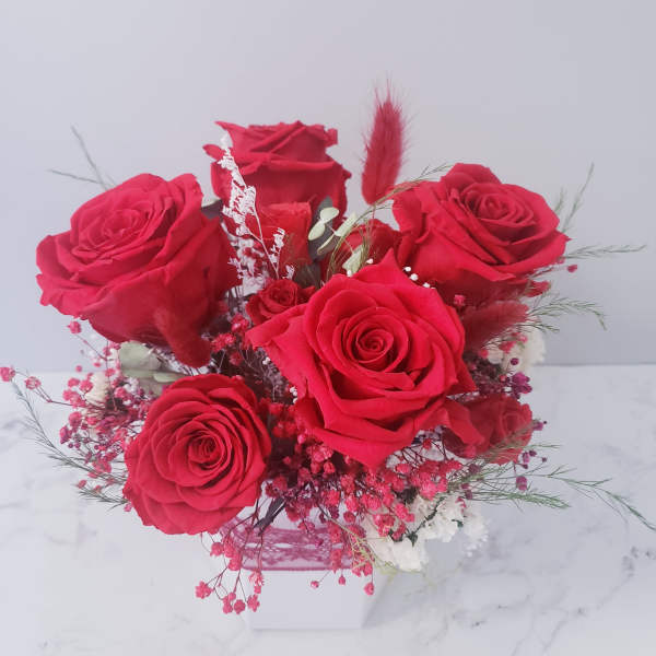 Bouquet of red roses in a white box with pink filler flowers
