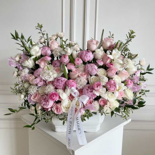 Large pink and white rose arrangement in a white vase