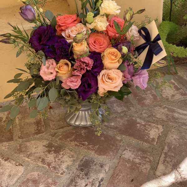 Mixed bouquet of roses and lisianthus in a silver vase with a ribbon