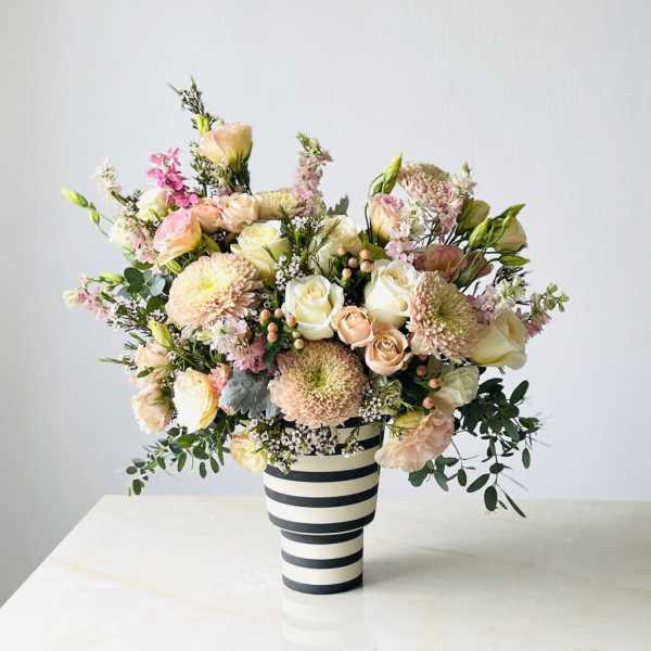 Pastel bouquet of roses and chrysanthemums in a striped vase