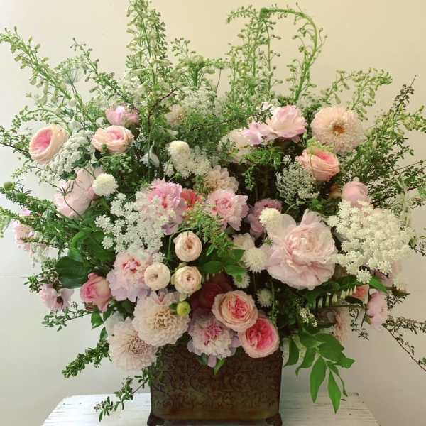 Large pink and white floral arrangement in a decorative container