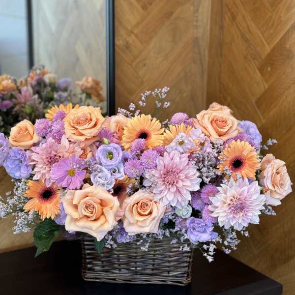 Peach roses and lavender flowers in a wicker basket