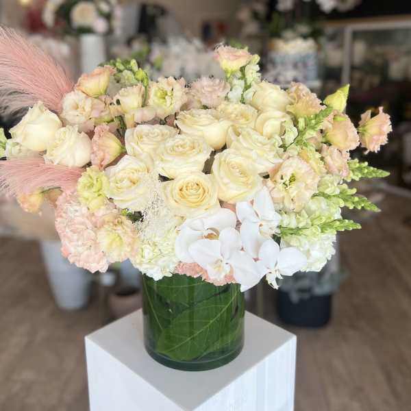 Cream and blush bouquet of roses, orchids, and snapdragons in a glass vase