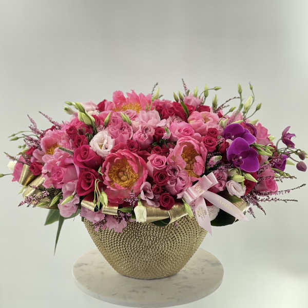 Pink and purple flower arrangement in a gold textured vase