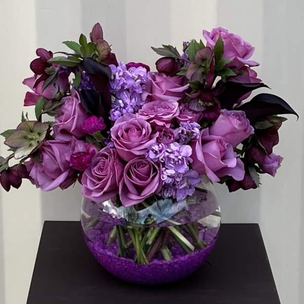 Purple rose bouquet in a round glass vase