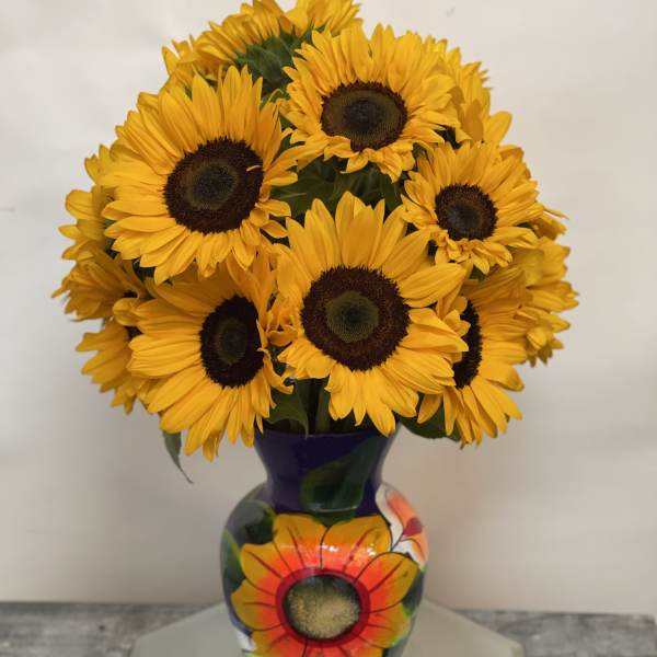 Bouquet of yellow sunflowers in a painted purple vase