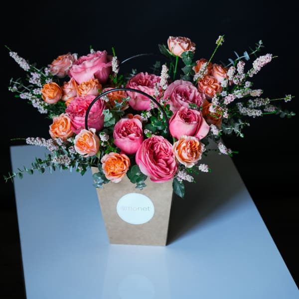 Pink and peach roses arranged in a kraft paper gift bag
