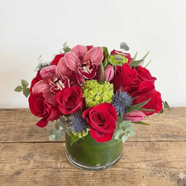 Red roses and pink orchids arranged in a glass vase