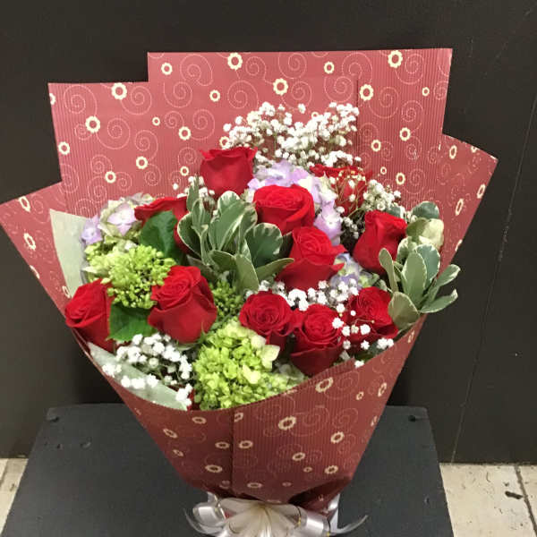 Bouquet of red roses with white filler flowers in patterned wrapping