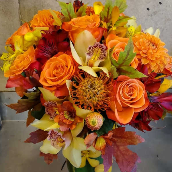 Orange and yellow mixed bouquet in a green vase