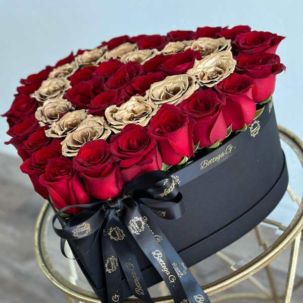 Heart-shaped box of red and gold roses with a black ribbon