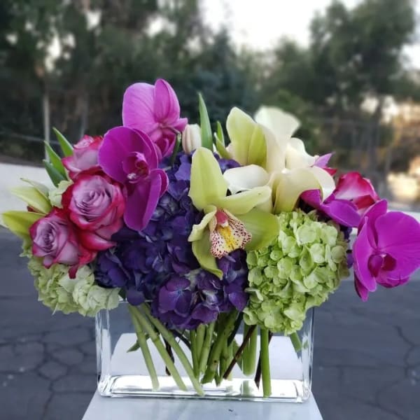 Bouquet of orchids, hydrangeas, and roses in a clear glass vase